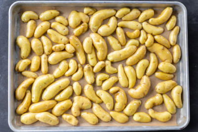 Potatoes facing down on a baking sheet.