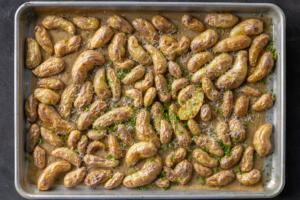 Roasted potatoes with herbs and parmesan on a sheetpan.