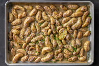 Roasted potatoes with herbs and parmesan on a sheetpan.