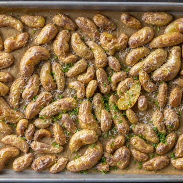 Roasted potatoes with herbs and parmesan on a sheetpan.