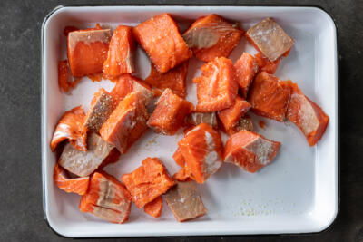 Seasoned salmon pieces on a tray.