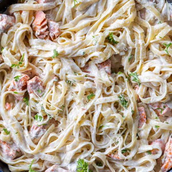 Salmon Alfredo in a serving pan with herbs and Parmesan.