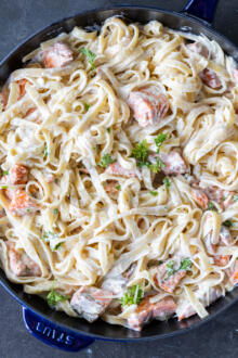 Salmon Alfredo in a pan with herbs.