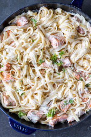 Salmon Alfredo in a pan with herbs.