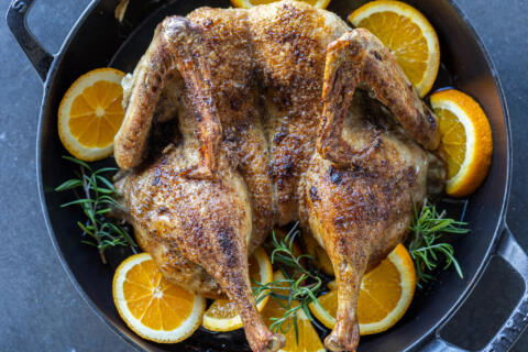 Serving pan with Spatchcock Duck and oranges around.