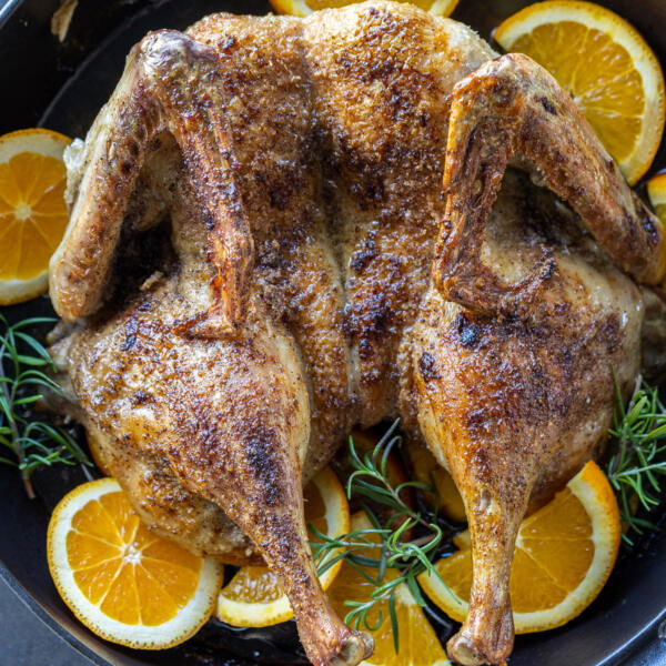 Serving pan with Spatchcock Duck and oranges around.
