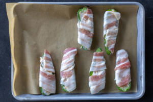 Wrapped jalapeno on a baking sheet.