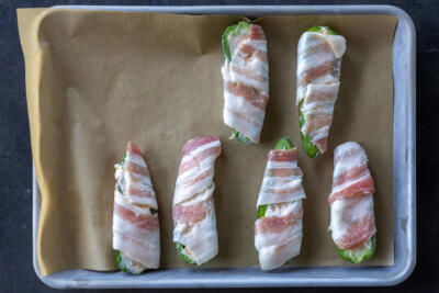 Wrapped jalapeno on a baking sheet.