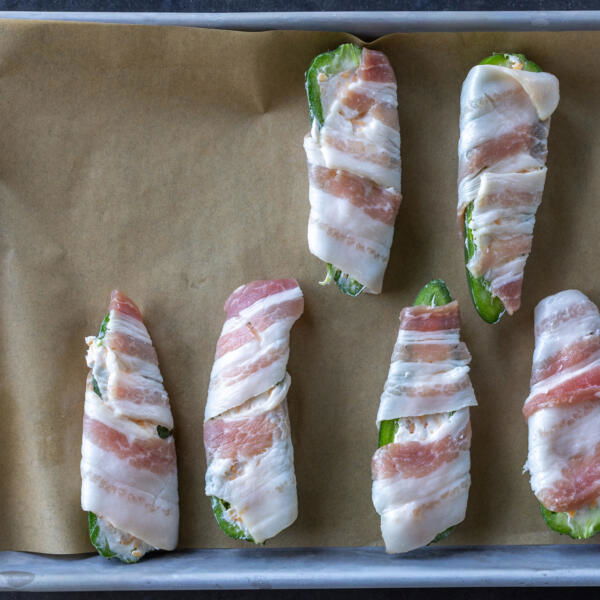 Wrapped jalapeno on a baking sheet.