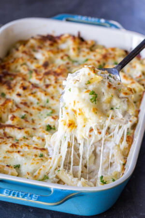 A spoon with Baked Chicken Alfredo in a pan.