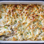A pan with Baked Chicken Alfredo with spoon.