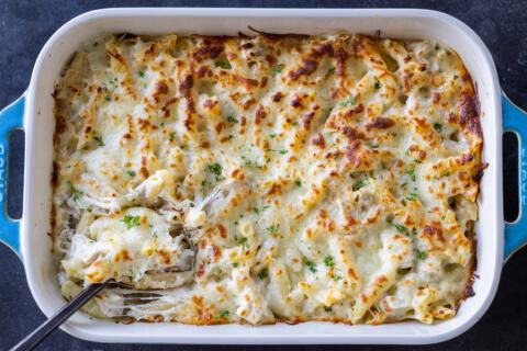 A pan with Baked Chicken Alfredo with spoon.