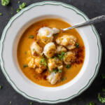 Creamy Lobster Bisque in a bowl with more lobster on top and herbs.
