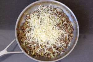 Onion, cheese, cabbage and meat in a pan.