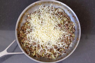 Onion, cheese, cabbage and meat in a pan.