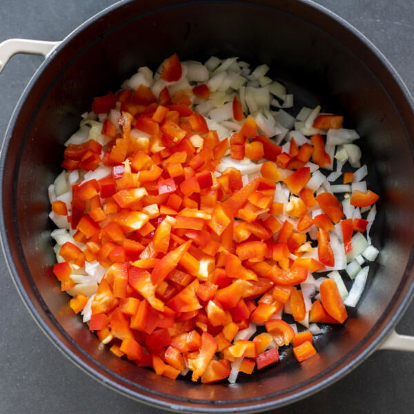 Chopped up veggies in a pot with oil cooking.
