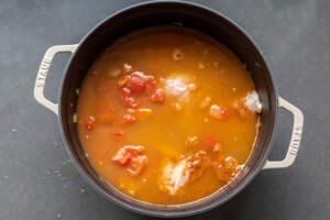 chicken added to veggies and broth in a pot.