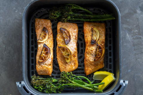 Air fryer basket with cooked salmon.