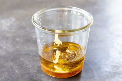A jar with all the ingredients for Honey Dijon Dressing.