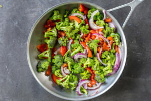 Broccoli, tomato, onion with garlic cooking in a pan.