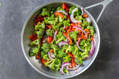 Broccoli, tomato, onion with garlic cooking in a pan.
