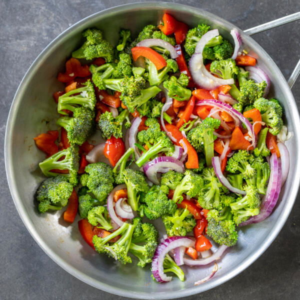 Broccoli, tomato, onion with garlic cooking in a pan.