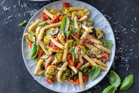 Pasta Primavera in a bowl with cheese and basil around.