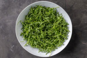 Arugula, oil and lemon in a bowl.