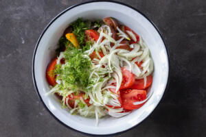 A bowl with tomatoes, onion and dill.