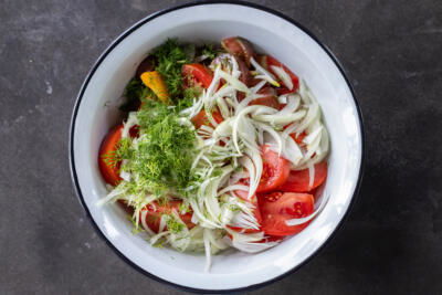 A bowl with tomatoes, onion and dill.