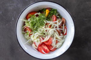 Tomatoes, onion, dill and seasoning in a bowl.