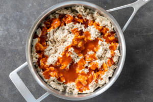 Chicken with enchilada sauce in a pan.