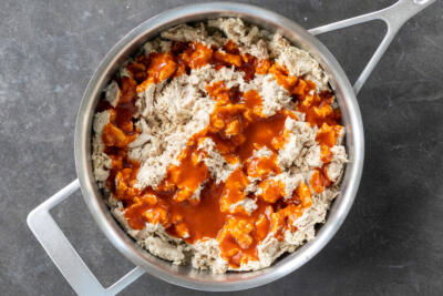 Chicken with enchilada sauce in a pan.