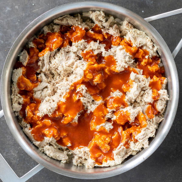 Chicken with enchilada sauce in a pan.