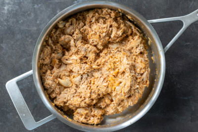 Cooked chicken with enchilada sauce with onion.