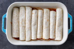 Chicken Enchiladas rolled up in a baking pan.