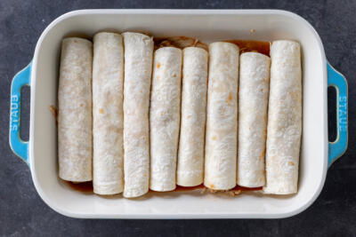 Chicken Enchiladas rolled up in a baking pan.