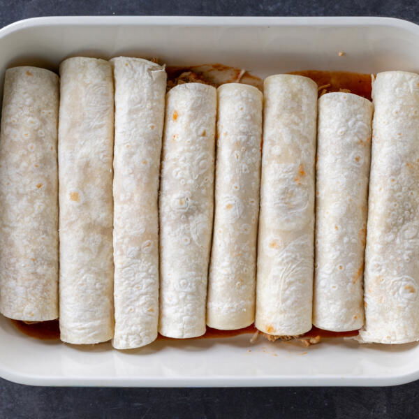 Chicken Enchiladas rolled up in a baking pan.