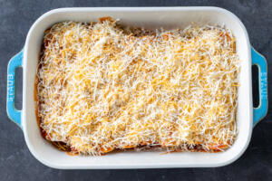 Baking dish with Chicken Enchiladas and cheese on top.