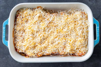 Baking dish with Chicken Enchiladas and cheese on top.