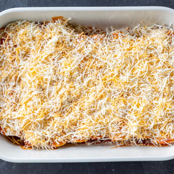 Baking dish with Chicken Enchiladas and cheese on top.