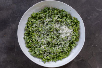 Kale, dressing and parmesan in a bowl.