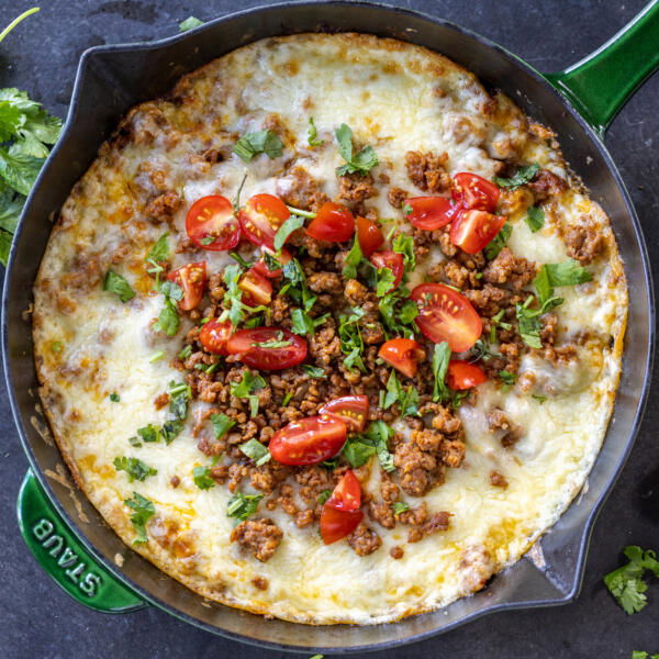Queso Fundido in a skillet with herbs.