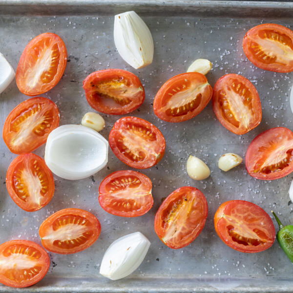 Tomatoes, onion, garlic and jalapeno on a baking sheet.