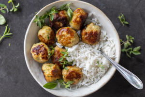 Turkey Zucchini Meatballs in a bowl with rice and herbs.