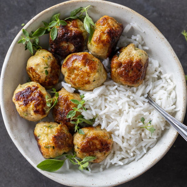 Turkey Zucchini Meatballs in a bowl with rice and herbs.