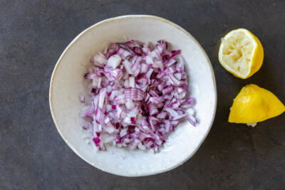 Diced onion with lemon juice in a bowl.