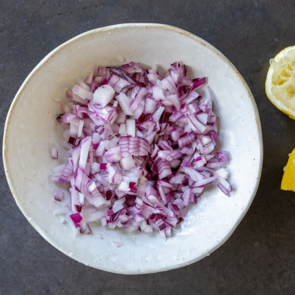 Diced onion with lemon juice in a bowl.
