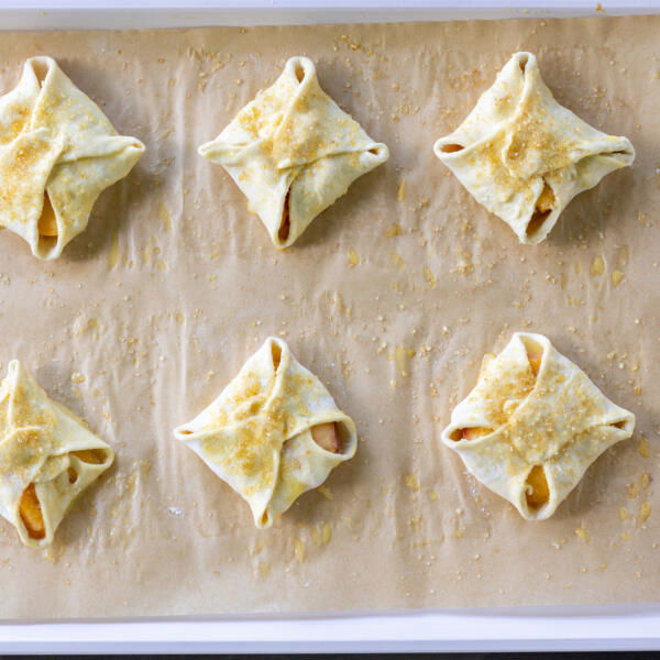 Peach Turnovers on a baking sheet prior to baking.