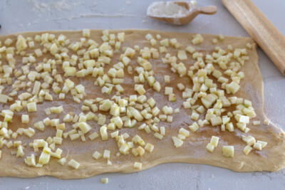 Rolled out dough with apple with sugar filling.